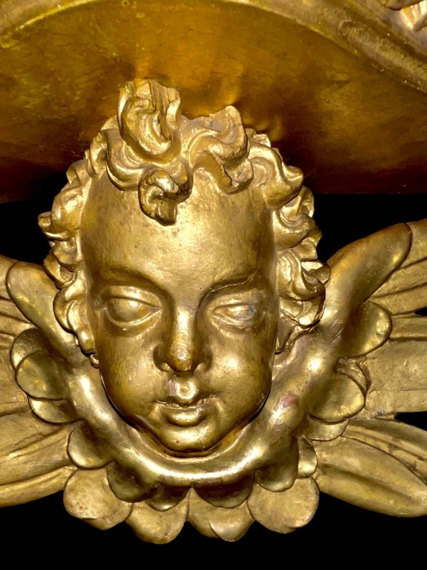Applique murale en bois sculpté et feuille d'or, ornée d'une tête d'ange chérubin.