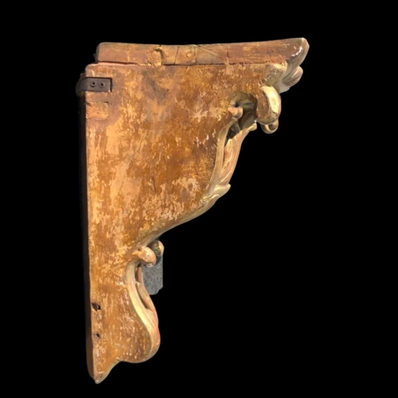 Étagère d'angle en bois sculpté et doré à la feuille, ornée de motifs végétaux stylisés.