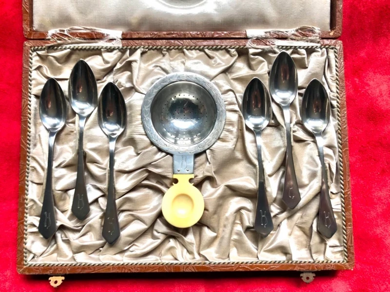 Set of six silver teaspoons with a silver tea strainer engraved with initials