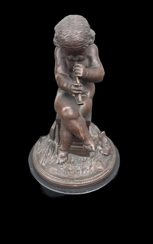 A small bronze sculpture depicting a cherub playing the flute.