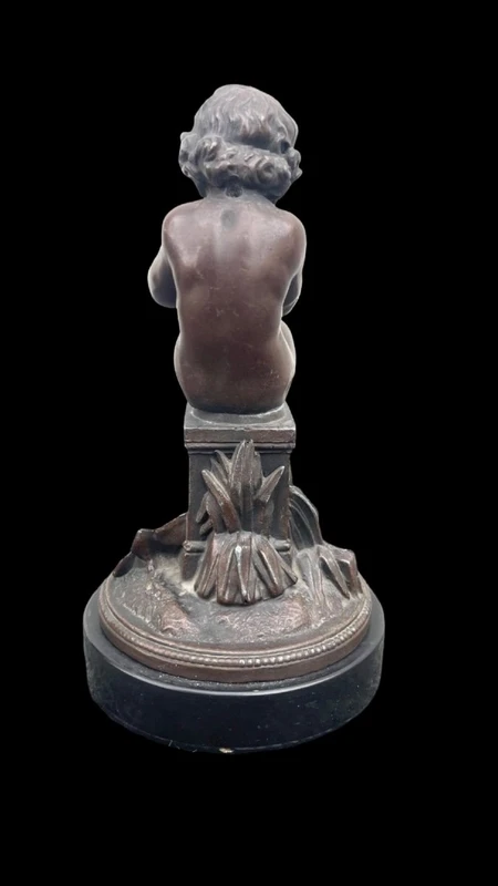 A small bronze sculpture depicting a cherub playing the flute.