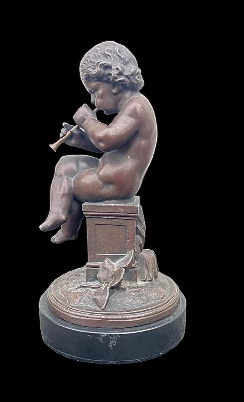 A small bronze sculpture depicting a cherub playing the flute.