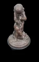 A small bronze sculpture depicting a cherub playing the flute.
