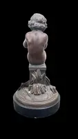 A small bronze sculpture depicting a cherub playing the flute.