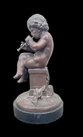 A small bronze sculpture depicting a cherub playing the flute.