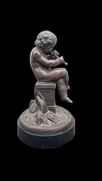 A small bronze sculpture depicting a cherub playing the flute.