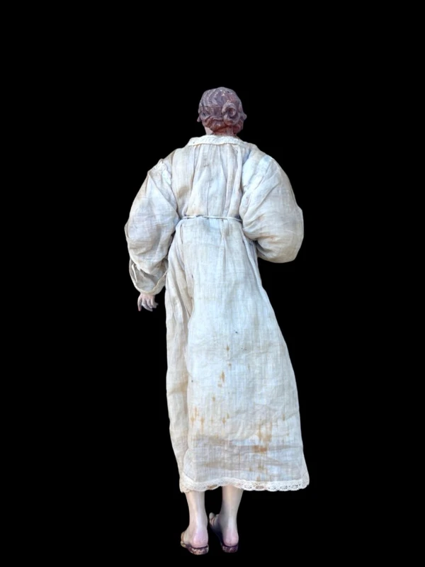 Nativity scene figurine with a terracotta face and a frame made of wood and fabric.