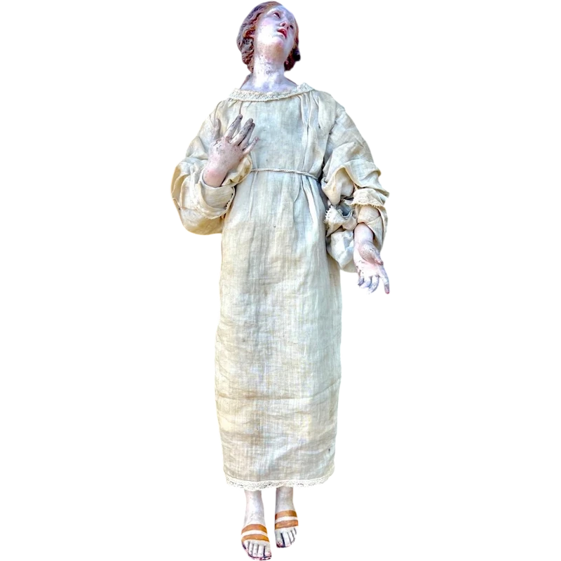 Nativity scene figurine with a terracotta face and a frame made of wood and fabric.