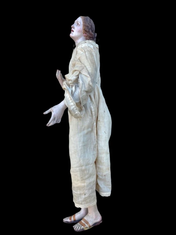 Nativity scene figurine with a terracotta face and a frame made of wood and fabric.
