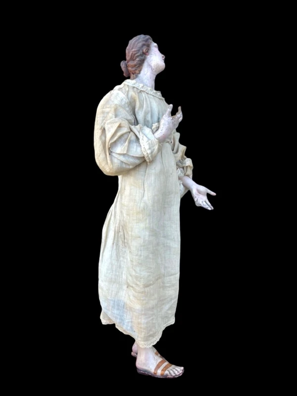 Nativity scene figurine with a terracotta face and a frame made of wood and fabric.