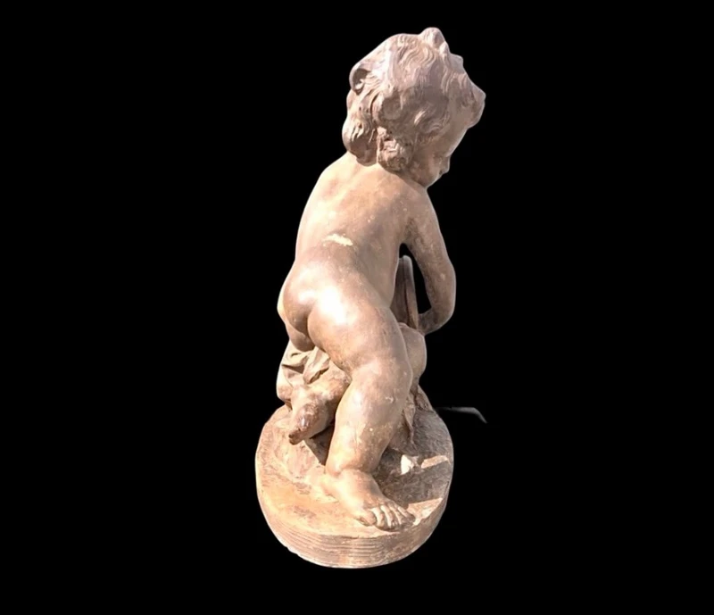A terracotta sculpture depicting a child pouring liquid from a vase.