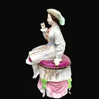 Porcelain tobacco box featuring a seated female figure holding a cigar.