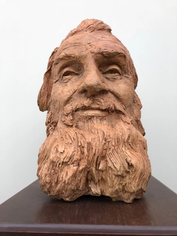 Terracotta sculpture depicting the head of a bearded man. Wooden base.