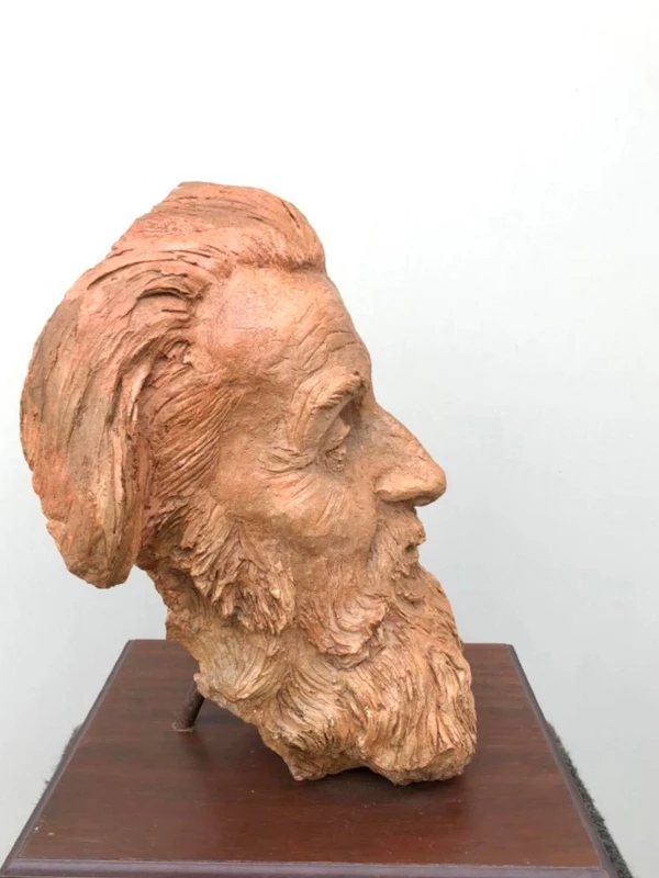 Terracotta sculpture depicting the head of a bearded man. Wooden base.