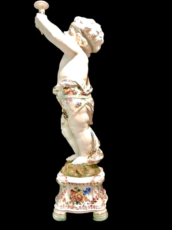 A pair of large majolica candlesticks featuring cherubs and polychrome floral decoration.