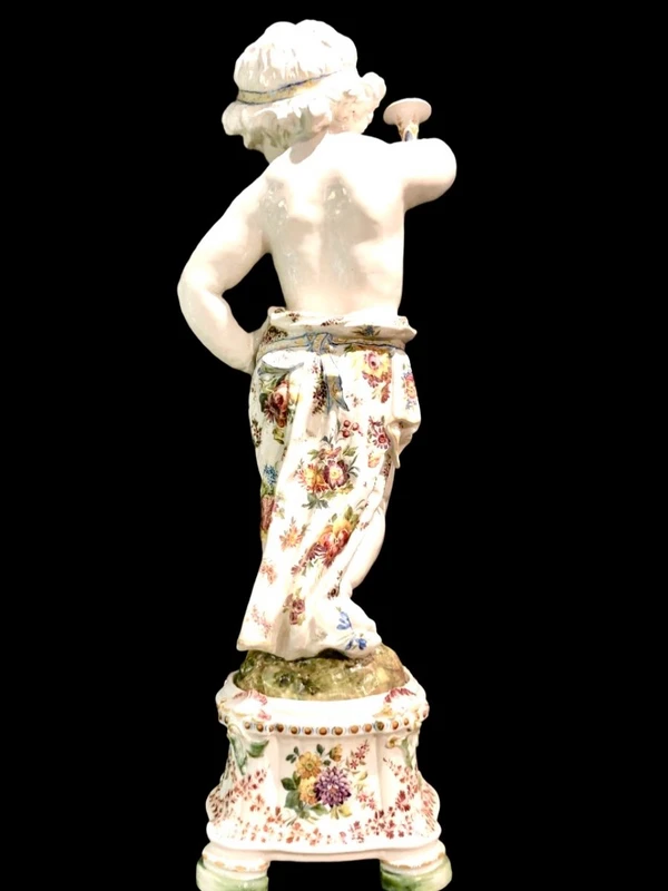 A pair of large majolica candlesticks featuring cherubs and polychrome floral decoration.