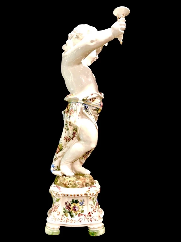 A pair of large majolica candlesticks featuring cherubs and polychrome floral decoration.
