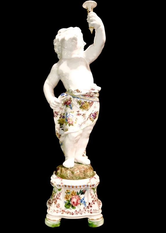 A pair of large majolica candlesticks featuring cherubs and polychrome floral decoration.