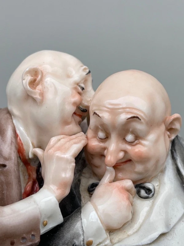 Sculpture caricaturale en porcelaine représentant deux amis qui se chuchotent à l'oreille.