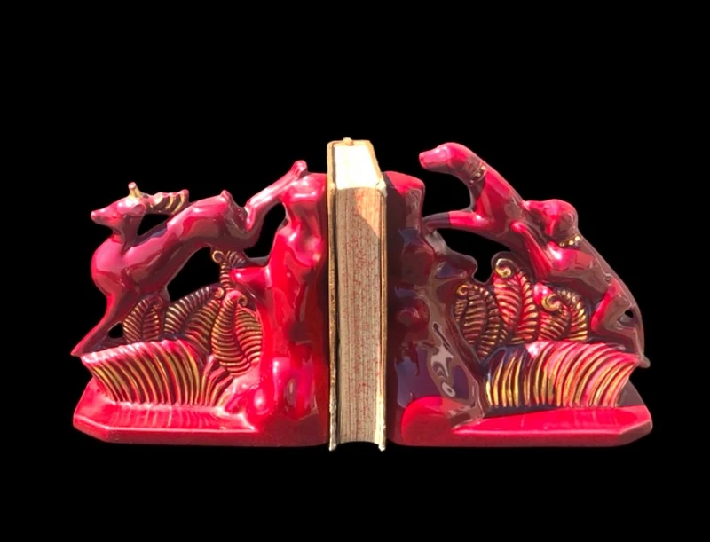 A pair of earthenware bookends depicting dogs chasing a deer.