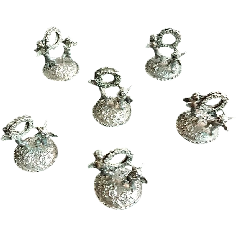 Serie di sei segnaposti in argento con coppia di putti che reggono una ghirlanda.