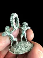 Serie di sei segnaposti in argento con coppia di putti che reggono una ghirlanda.