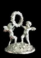 Serie di sei segnaposti in argento con coppia di putti che reggono una ghirlanda.