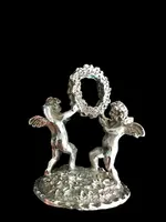 Serie di sei segnaposti in argento con coppia di putti che reggono una ghirlanda.
