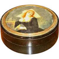 A small papier-mâché box with a miniature figure depicting a lady with a little bird.