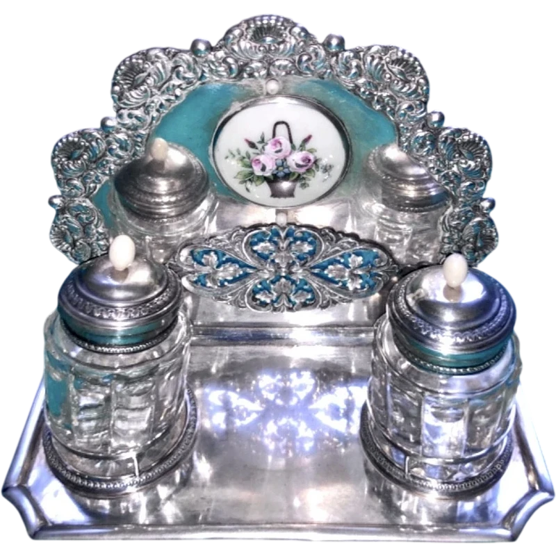 An inkwell made of embossed and openwork silver with stylized plant motifs and an enamel medallion.