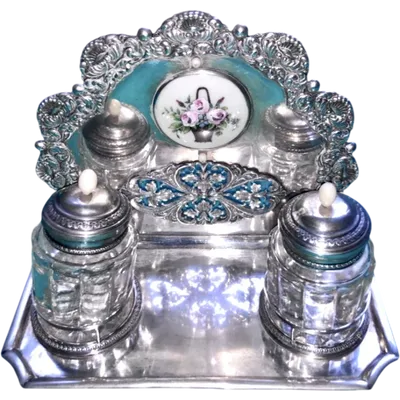 An inkwell made of embossed and openwork silver with stylized plant motifs and an enamel medallion.