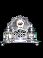 An inkwell made of embossed and openwork silver with stylized plant motifs and an enamel medallion.