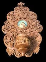 Acquasantiera in legno scolpito con motivi vegetali stilizzati e volute rocaille.