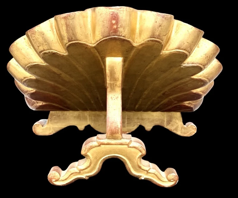 A shell-shaped lectern made of carved and gilded wood with rocaille motifs.
