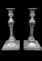 Coppia di candelieri in argento con decoro a motivi geometrici,teste di caproni,vasi,festoni