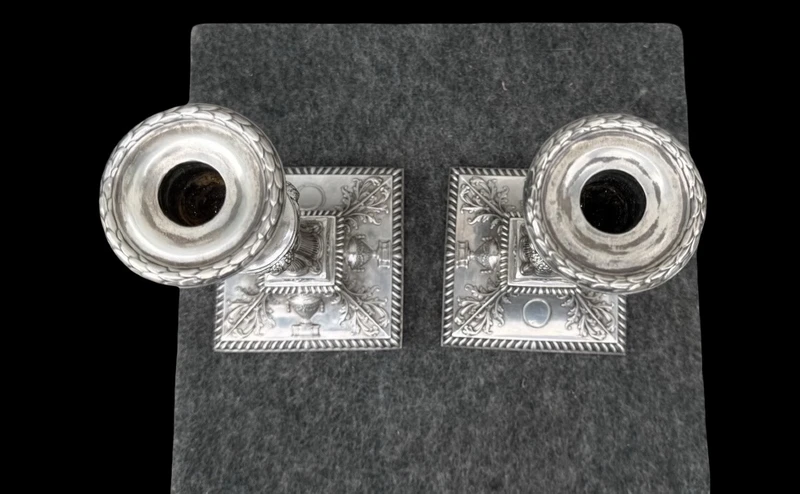 Coppia di candelieri in argento con decoro a motivi geometrici,teste di caproni,vasi,festoni