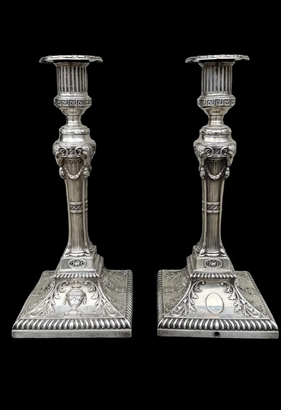 Coppia di candelieri in argento con decoro a motivi geometrici,teste di caproni,vasi,festoni