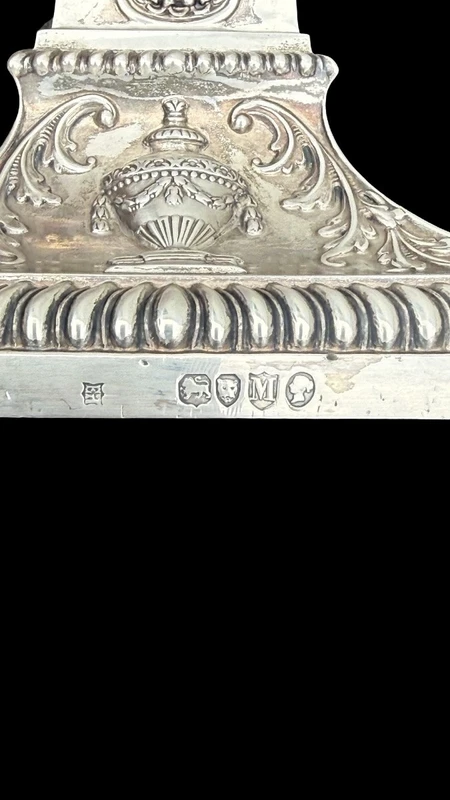 Coppia di candelieri in argento con decoro a motivi geometrici,teste di caproni,vasi,festoni