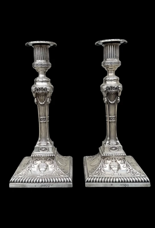Coppia di candelieri in argento con decoro a motivi geometrici,teste di caproni,vasi,festoni