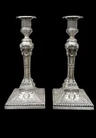 Coppia di candelieri in argento con decoro a motivi geometrici,teste di caproni,vasi,festoni