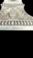 Coppia di candelieri in argento con decoro a motivi geometrici,teste di caproni,vasi,festoni
