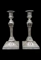 Coppia di candelieri in argento con decoro a motivi geometrici,teste di caproni,vasi,festoni