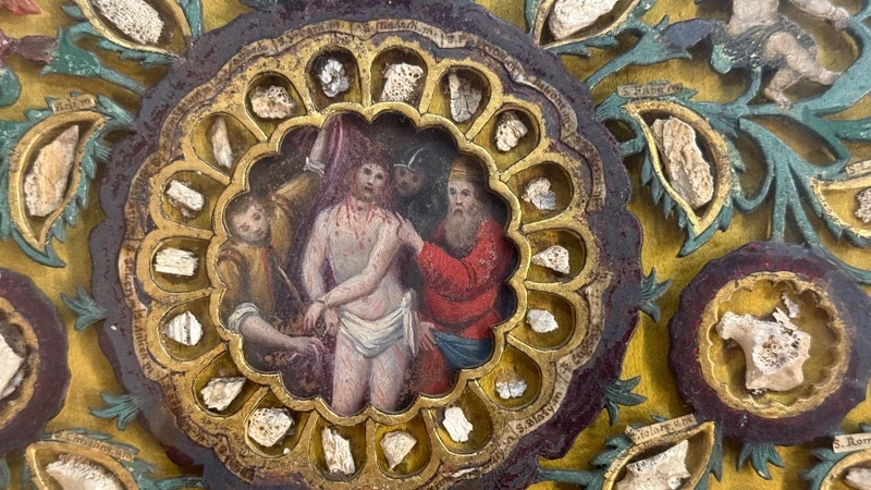 Quadro reliquiario con composizione in legno traforato in rilievo con putti e motivi vegetali.
