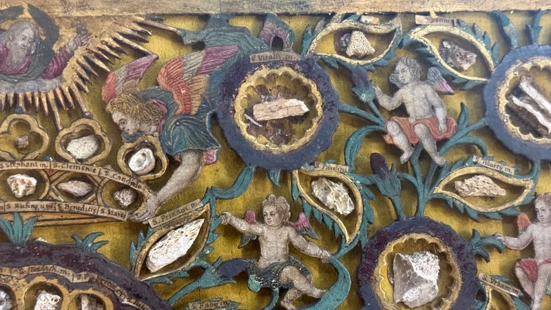 Quadro reliquiario con composizione in legno traforato in rilievo con putti e motivi vegetali.