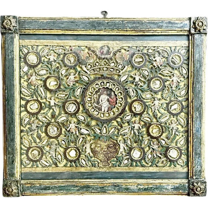 Quadro reliquiario con composizione in legno traforato in rilievo con putti e motivi vegetali.