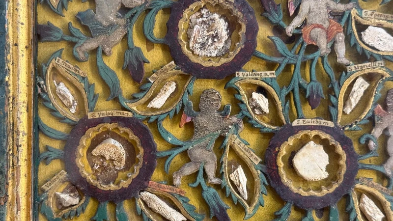 Quadro reliquiario con composizione in legno traforato in rilievo con putti e motivi vegetali.