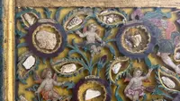 Quadro reliquiario con composizione in legno traforato in rilievo con putti e motivi vegetali.