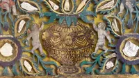 Quadro reliquiario con composizione in legno traforato in rilievo con putti e motivi vegetali.