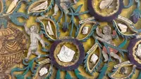 Quadro reliquiario con composizione in legno traforato in rilievo con putti e motivi vegetali.