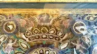 Quadro reliquiario con composizione in legno traforato in rilievo con putti e motivi vegetali.